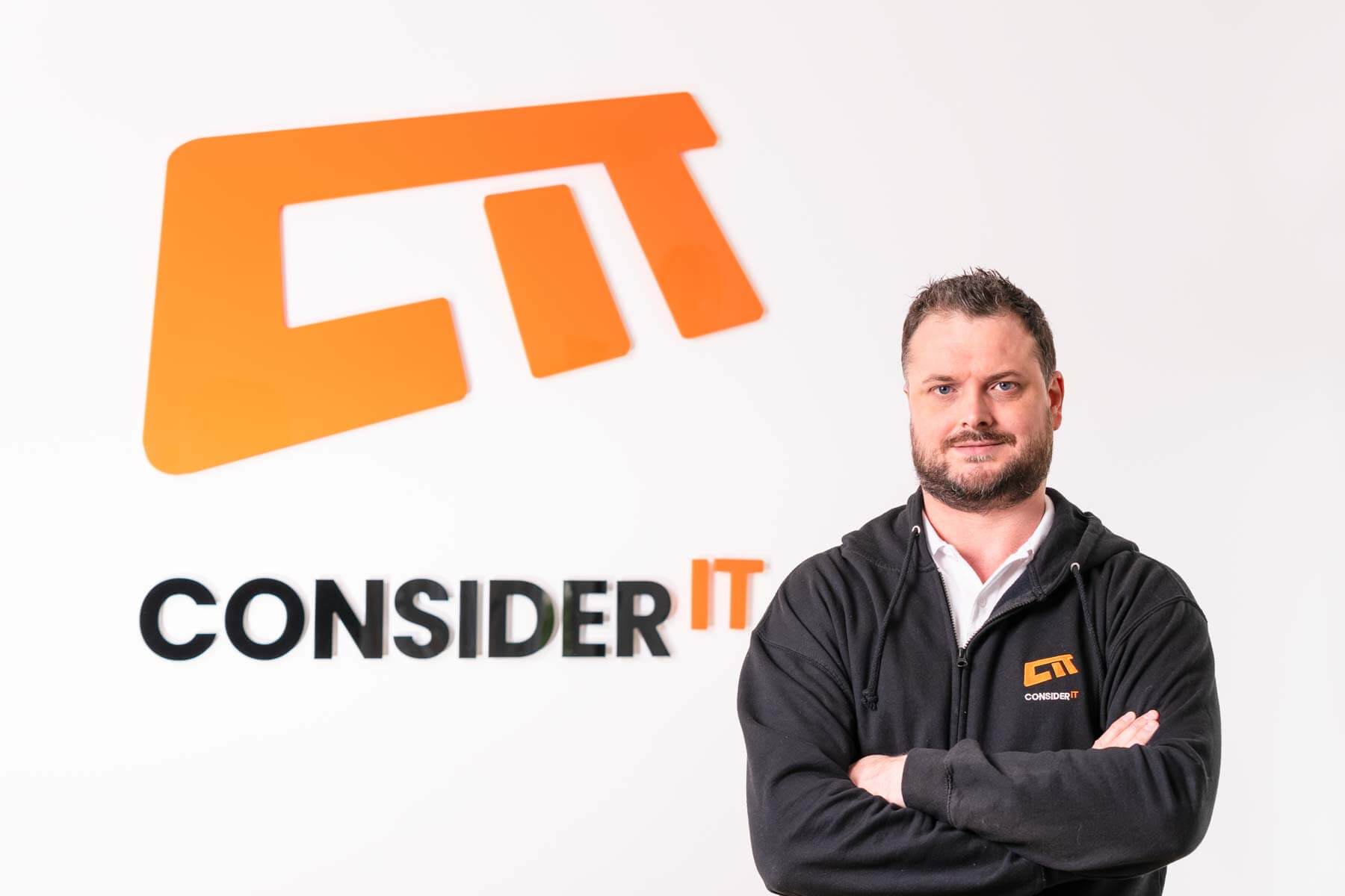 A picture of Stuart Gilbertson Consider IT's Managing Director standing by the Consider IT logo.